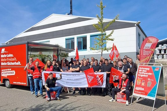 Menschen mit IG Metall Banner und Fahnen vor dem DGB-Frittenmobil